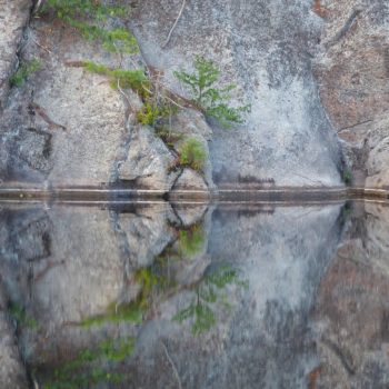 Reflection of the rock on the perfectly still early morning lake.