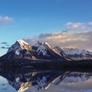 A beautiful winter scene of mountains reflecting on Abraham Lake in Alberta.