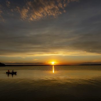 Sunset with a canoe crossing Waskesiu Lake.