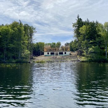 A partially constructed, large, 2-level home is surrounded by land that has been completely cleared of all trees and vegetation, all the way down to the lakefront. The forest remains intact on the sid ...
