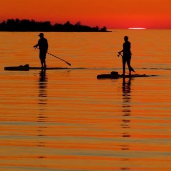 Paddle boarders enjoying the sunset at Lake Huron.