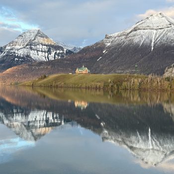 A beautiful sunrise on Waterton Lake on a rare calm morning, with the Prince of Whales Hotel in the spotlight of the rising sun.