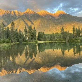 A stunning completely unedited shot of the steeples range of the Rocky Mountains reflects in the water almost at sunset August 2023.