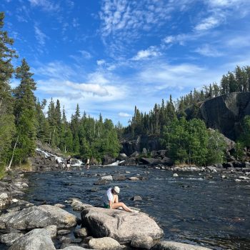 Photo of me sitting at the base of Cameron Falls in the NWT after hiking up to the falls with some friends.